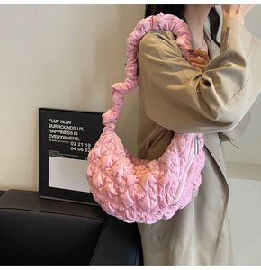 Pink quilted cloud bag with pleated handle shown from 45-degree angle on a female model