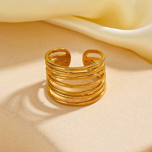 Golden multi-layer wide open ring with textured hammered finish on beige pedestal