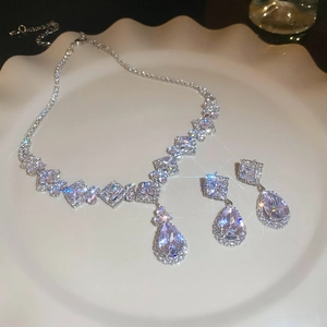 Close-up of elegant silver necklace and drop earrings set with sparkling zircons