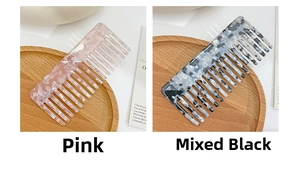 Close-up of pink and black marble acetate wide-tooth hair combs on a wooden tray