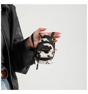 Close-up of mini cow print crossbody bag with fashion label held by a model
