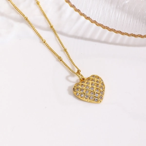 Detailed view of an 18k gold plated heart pendant with grid texture and crystals