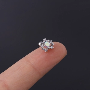 Macro shot of silver snowflake ear stud with iridescent zircon on fingertip for size