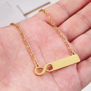 Handheld gold stainless steel necklace featuring infinity symbol and vertical bar pendant