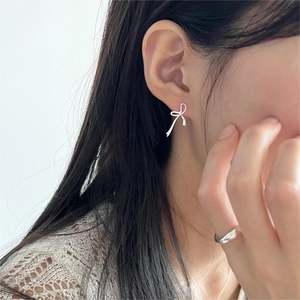 Close-up of minimalist silver bow stud earrings worn by a model for a refined look