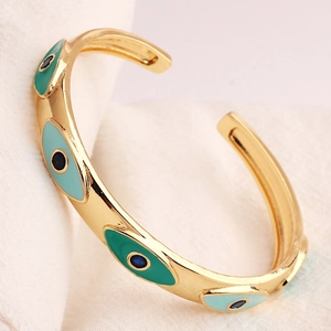 Golden open evil eye cuff bracelet with blue enamel inlay and polished metallic finish