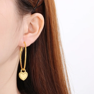 Detail of gold twisted rope hoop earrings with a textured heart lock pendant