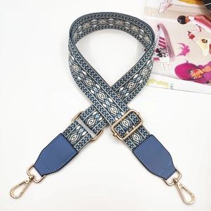 Detail of blue and beige jacquard strap with leather ends and gold-tone metal hooks