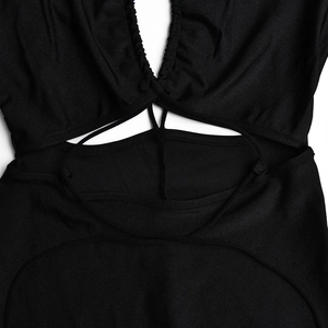 Détail de la combinaison noire avec décolleté en V, découpe à la taille et lacets croisés