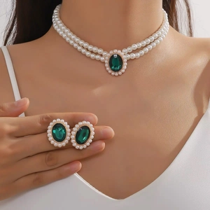 Close-up of double-layer pearl necklace and earrings with green oval stones and gold finish