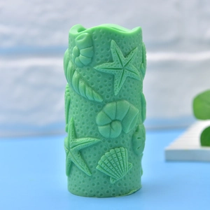 Green cylindrical candle with embossed sea shells and starfish marine theme design