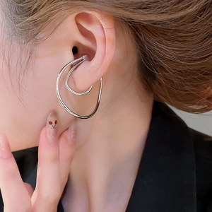 Close-up of silver irregular double oval ear cuff worn on model's ear cartilage