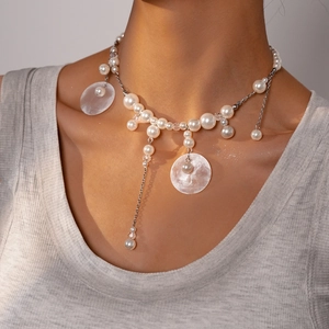 Detail of beaded choker necklace with white pearls and shell pendant on a female model