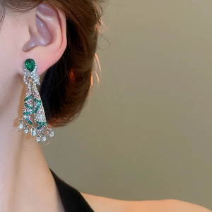 Close-up of model wearing silver tassel earrings with green and pink gemstones