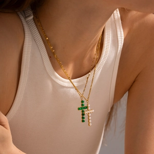 Detail of gold cross necklaces with green beads and white pearls on a female model