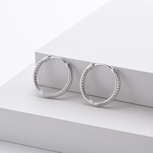 Détail macro de boucles d'oreilles créoles en argent serties de zircons brillants