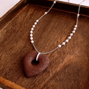 Detail of dark brown volcanic stone heart pendant on beaded silver chain necklace
