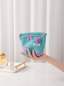 Plush mint green cosmetic bag with purple bows and flower zipper held by model