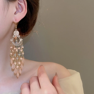 Detail of bohemian drop earrings featuring gold metal discs and light pink beaded tassels