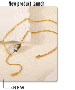 Close-up of golden necklace with blue bean pendant and lobster clasp on ceramic