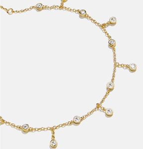 Detailed macro view of gold chain anklet featuring round clear cubic zirconia charms