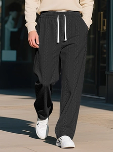 Close-up of black cable-knit texture and contrasting white drawstring on casual pants