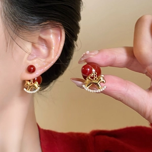 Close-up of zircon flocked pony stud earring with red pearl and gold horse pendant