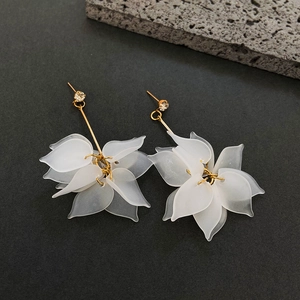 Macro view of crystal flower earrings with matte white petals and gold stems
