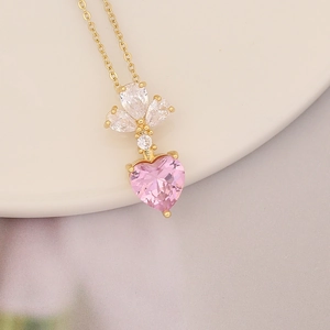 Macro view of 18K gold plated necklace with a pink heart pendant and white stones