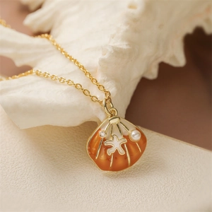 Golden seashell pendant necklace with orange enamel, starfish and pearl detail on white background