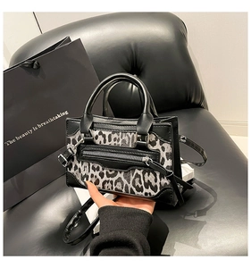Detalle de bolso con estampado de leopardo, costuras de cuero negro y bolsillo con cremallera