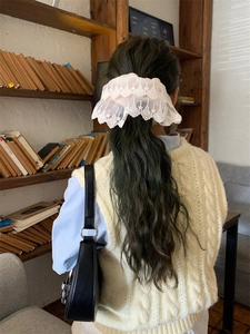 Detail of elegant cream lace scrunchie worn on a ponytail in a cozy aesthetic setting