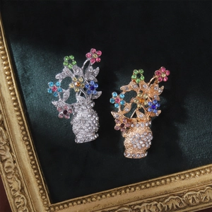 Detailed close-up of gold and silver flower vase brooches with colorful rhinestones