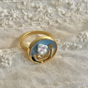 Detail of vintage gold ring with blue enamel and white floral relief on lace