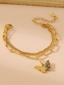 Détail d'un bracelet double couche doré avec pendentif papillon et chaînes à maillons divers