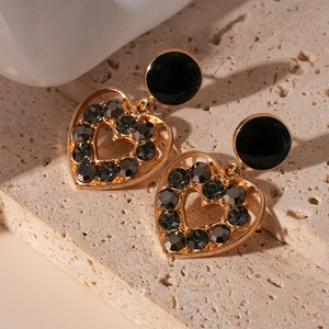 Détail de boucles d'oreilles cœur vintage avec cristaux gris sur travertin et soie