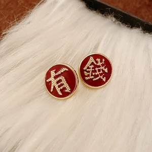 Macro detail of Chinese New Year stud earrings with red enamel and golden characters