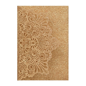 Macro shot of glittery gold laser-cut wedding invitation envelope with lace patterns