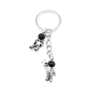 Macro shot of two vintage astronaut pendants on a silver alloy keychain with polished finish