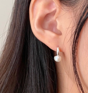 Close-up of a sterling silver pearl drop earring worn by a model for a refined look