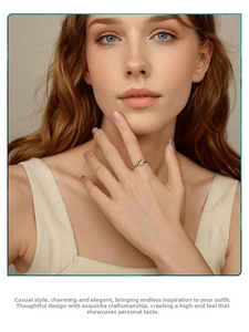 Close-up of a silver heart ring with gold accents worn by a model in soft lighting