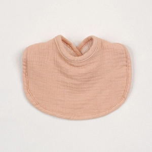 Close-up of soft multi-layer cotton muslin baby bib in peach color with ruffled texture