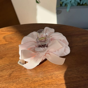 Elegant cream pink puff ribbon hair claw clip with bow detail on a rustic wooden surface