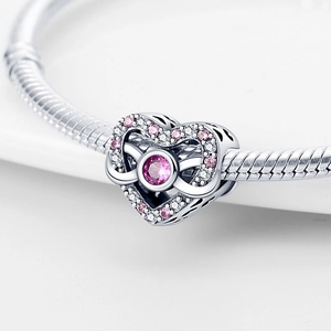 Macro view of silver heart charm with pink cubic zirconia on a snake chain bracelet