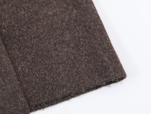 Gros plan sur la texture épaisse en laine marron et les coutures du manteau long