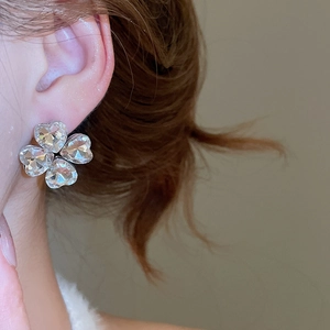 Close-up of elegant silver four-leaf clover crystal earrings with a polished transparent finish