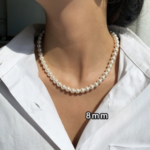 Detail shot of 8mm pearl pendant necklace on white shirt showing lustrous texture