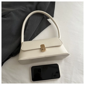 Detailed view of white PU leather baguette bag with gold buckle next to smartphone