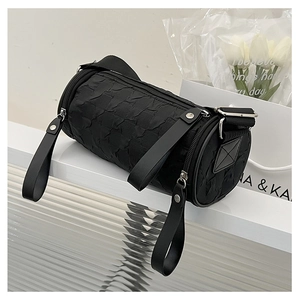 Detail of black cylindrical crossbody bag featuring a pleated texture and silver hardware