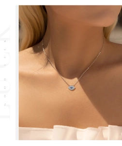 Detailed view of S925 sterling silver evil eye necklace with blue zircons on model neck